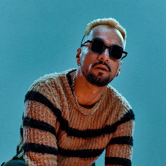 Dombresky wearing sunglasses and a striped sweater against a blue background